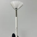 Makeup brush with white bristle head held by a hand wearing a black glove on a gray background